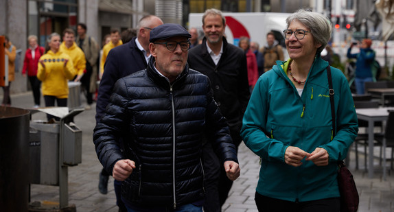 Ein Mann und eine Frau laufen nebeneinander durch eine Fußgängerzone.